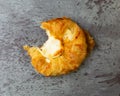 Top view of a delicious cream cheese danish missing a bite on a gray mottled tabletop