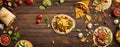 Top view of delicious Mexican tacos and ingredients on wooden table, corn tortilla, vegetables and condiments, wide banner,