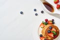 Top view of delicious pancakes with maple syrup, blueberries and strawberries on plate on marble white surface Royalty Free Stock Photo