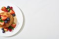 Top view of delicious pancakes with maple syrup, blueberries and strawberries on plate on marble white surface Royalty Free Stock Photo