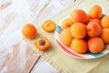 Top view of Delicious ripe orange apricots in a bright plate on wooden background with green napkin. Fresh juicy fruits.