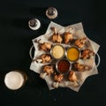 top view of delicious roasted chicken with various sauces on baking paper, spices and glass of beer Royalty Free Stock Photo