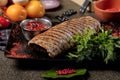 Top view delicious steak. Cooked Pork Loin Roast, red bbq sauce, greens with vegetables and spices on black stone Royalty Free Stock Photo