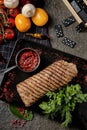 Top view delicious steak. Cooked Pork Loin Roast, red bbq sauce, greens with vegetables and spices on black stone Royalty Free Stock Photo