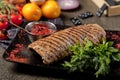 Top view delicious steak. Cooked Pork Loin Roast, red bbq sauce, greens with vegetables and spices on black stone Royalty Free Stock Photo