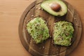 Top view of delitious vegan sandwich with guacamole and micro greens on top. Half of avocado with sandwich on wooden