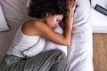 Top view of depressed and sad young African American woman lying down on the bed crying while hugging pillow. Royalty Free Stock Photo