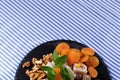 Top view of a desert. Dry apricots, walnuts and mint on a plate of turkish delight on a striped background. Copy space.
