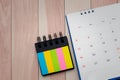 Top view of desk calendar and index sticky note on wooden table background with copy space
