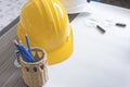 Top view of desk of engineering project in construction site or office with stationery and yellow safety helmet. Construction and