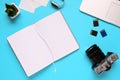 Top view of a desktop of a photographer consisting on a camera, a laptop, a notebook and a memory card on a blue desk background - Royalty Free Stock Photo