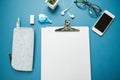 Top View Desktop: a sheet of paper, pencils, phone, glasses, headphones on a blue background.