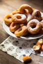 Top view detail on a bunch of fresh homemade donuts (doughnuts) on a white plate, with sugar bowl, rolling pin