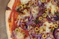 Top view detail closeup studio shot of freshly baked pizza al tonno on baking paper. Olives, tuna, onion, veggies, crust