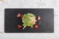 Top view of Diced salmon salad with avocado, tomato, onion, chilli, and coriander served in black rectangle stone plate on washi.