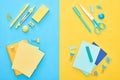 Top view of different colorful stationery with yellow and blue notepads on bicolor background.