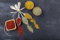 Top view of different kinds of colorful spices in spoons on black stone surface. Creative food concept texture with blank copy Royalty Free Stock Photo