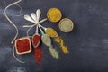 Top view of different kinds of colorful spices in spoons on black stone surface. Creative food concept texture with blank copy Royalty Free Stock Photo