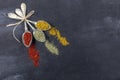 Top view of different kinds of colorful spices in spoons on black stone surface. Creative food concept texture with blank copy Royalty Free Stock Photo