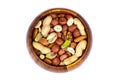 Top view of different nuts mix: almonds, pistachios, peanuts, hazelnuts heap in round brown wooden bowl isolated on white