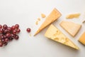 Top view of different types of cheese and grapes on white