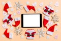 Top view of digital tablet with Christmas decorations and Santa hats on orange background. Happy holiday concept Royalty Free Stock Photo