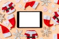 Top view of digital tablet with Christmas decorations and Santa hats on orange background. Happy holiday concept Royalty Free Stock Photo