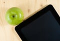 Top of view of digital tablet pc and green apple on wood table