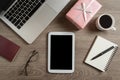 Top view of digital tablet, pink gift box, passport, eyeglasses, pen, notebook, cup of coffee and laptop computer Royalty Free Stock Photo