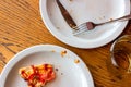 Top view of dirty messy plates after pizza eating with unclean used utensils in the cafe.