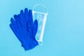 Top view of disposable medical mask and nitrile gloves on blue background. Personal protection concept with copy space Royalty Free Stock Photo