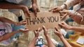 Top view of diverse young volunteers holding card with Thank you lettering while standing in charitable organization