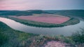 Top view of Dnestr river at sunrise. River is covered with mist and surrounded with green forest and fields.