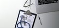 Doctor desk Laptop computer Stethoscope, clipboard on desk and interns on background Royalty Free Stock Photo