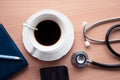 Top view of doctor desk with hot black coffee stethoscope and smartphone