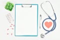 Top view of doctor desk table with stethoscope, eyeglass, pills and blank paper on clipboard with pen. copy space Royalty Free Stock Photo