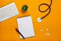 Top view of doctor`s desk with stethoscope keyboard notepad and pen, prescription and pills