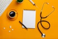 Top view of a doctor`s table with notepad and pen stethoscope, keyboard, prescription and pills, a cup of coffee on a yellow Royalty Free Stock Photo