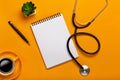 Top view of a doctor`s table with notepad and pen stethoscope, keyboard, prescription and pills, a cup of coffee on a yellow Royalty Free Stock Photo