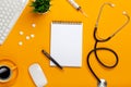 Top view of a doctor`s table with notepad and pen stethoscope, keyboard, prescription and pills, a cup of coffee on a yellow Royalty Free Stock Photo