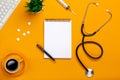 Top view of a doctor`s table with notepad and pen stethoscope, keyboard, prescription and pills, a cup of coffee on a yellow Royalty Free Stock Photo