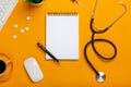 Top view of a doctor`s table with notepad and pen stethoscope, keyboard, prescription and pills, a cup of coffee on a yellow Royalty Free Stock Photo