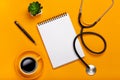 Top view of a doctor`s table with notepad and pen stethoscope, keyboard, prescription and pills, a cup of coffee on a yellow Royalty Free Stock Photo