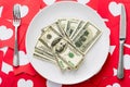 View of dollar banknotes on white plate near knife and fork on red paper cut cards with hearts symbols Royalty Free Stock Photo