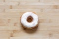 Top view of donut sprinkled with white powder, on wooden table.