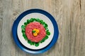 Top view of double plated beef steak tartare served with three raw quail egg yolks and surrounded by watercress leaves on a Royalty Free Stock Photo