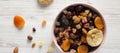 Top view, dried fruits and nut mix in a pink bowl on white wooden surface. Overhead, from above, overhead