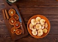 top view of dried orange slices with kitchen knife on a wooden cutting board and dried apple slices on a plate on wooden