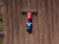 Top view from drone of big tractor with cultivator ploughs field