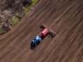 Top view from drone of big tractor with cultivator ploughs field